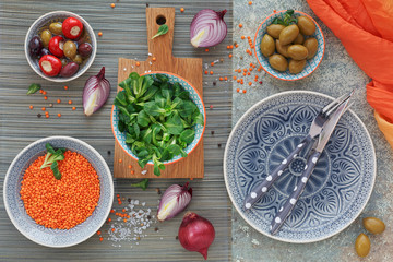 Green and black olives, loaf of fresh multigrain bread, corn salad and red onion over old wood background.