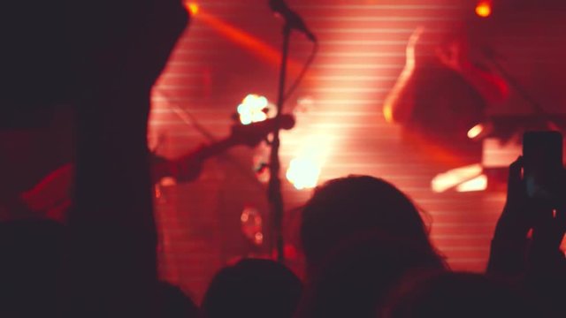 Fans making heart with hands and hold the phone with digital displays at a rock concert in a night club. 3840x2160