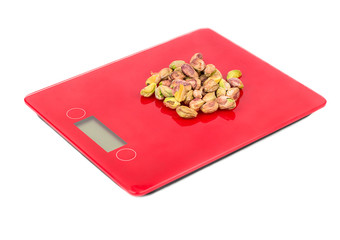 Pistachio nuts without shell on red scales on white background