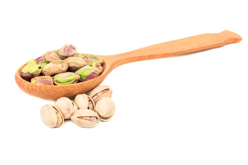 Pistachios without shell in a wooden spoon with scattered nuts on a white background