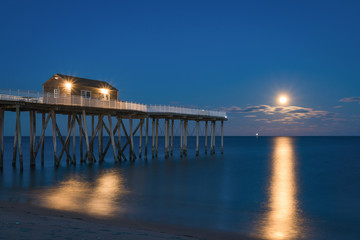 Obraz premium Full moon rising at Belmar Fishing Pier in New Jersey 