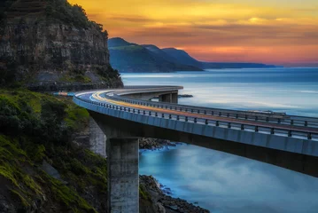 Deurstickers Zonsondergang over de Sea Cliff-brug langs de Australische kust van de Stille Oceaan met lichten van passerende auto& 39 s © Nick Fox