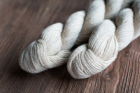 Close up view of white skein wool yarn for knitting, weaving an crocheting craft. on wooden surface