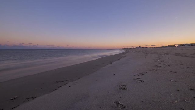 Calm waves crashing along the shoreline during a sunset