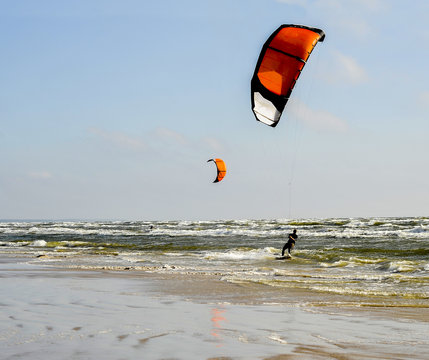 Jürmala (Latvia).  Kaitserfing at the sea  with a red parachute at strong wind and waves.
