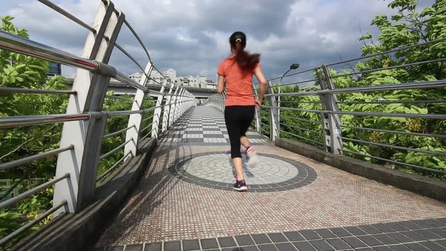 Rear view Athletic running fitness asian woman in a bridge of urban city a hot day of the summer in Taiwan. Exercising Concept. Sports lifestyle -Dan