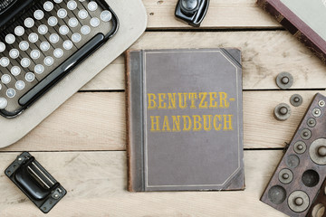 Benutzer-Handbuch, German text for User's Manual on old book cover at office desk with vintage items © MichaelJBerlin