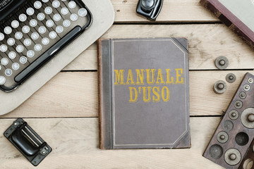 Manuale d'uso, Italian text for User's Manual on old book cover at office desk with vintage items © MichaelJBerlin