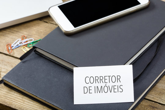 Corretor de imoveis, Portuguese text for Realtor business card on office desktop with electronic devices