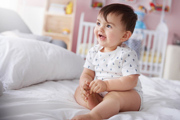 Adorable baby boy sitting on the bed