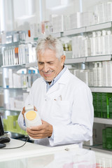 Senior Pharmacist Scanning Barcode Of Shampoo Bottle At Counter