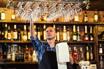 Barman at work in pub,Portrait of cheerful barman worker standing,Waiter giving menus,A pub.Bar.Restaurant.Classic.Evening.European restaurant.European bar.American restaurant.American bar.