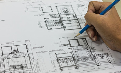 Hand of engineer use pencil sketch on machine's blueprint