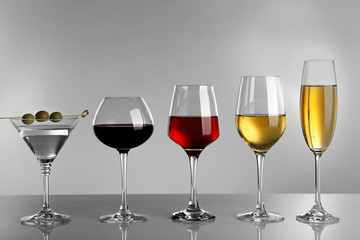 Glasses of wine and spirits on light background