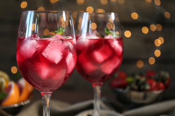 Glasses of delicious wine spritzer on blurred lights background