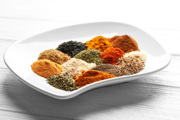 Plate with mix of different spices on wooden table