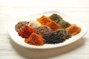 Plate with mix of different spices on wooden table