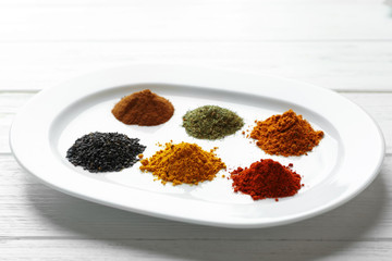 Plate with mix of different spices on wooden table