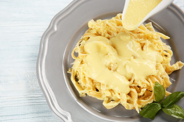 Adding cheese sauce to delicious pasta, closeup