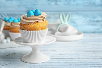 Cake stand with delicious Easter cupcake on wooden table
