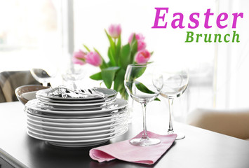 Stack of plates, cutlery with bouquet of tulips on a table.