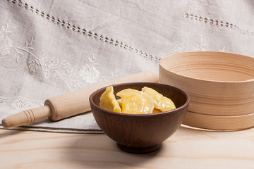 Fresh boiled varenyky or dumpling with cottage cheese or curd in clay bowl on wooden background.