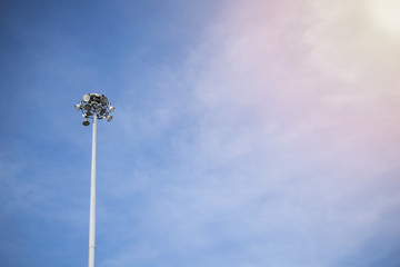 Lonely stadium light or lamp post with Union of light bulb standing alone with clould and blue sky.