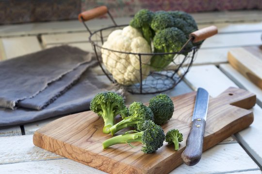Broccoli florets and kitchen knife on wooden board