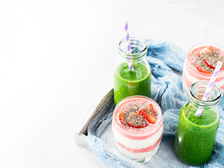 Healthy food concept green smoothie yogurt strawberries chia seeds breakfast on white gray tray blue textile. Fruit Vegetable juice glass bottle