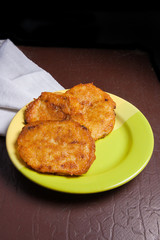 Potato pancakes with meat on green plate in Belarusian style on dark background.
