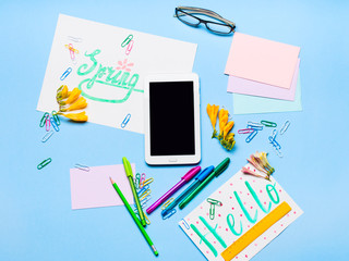 Blue pastel flat lay with gadget tablet stationery glasses spring lettering
