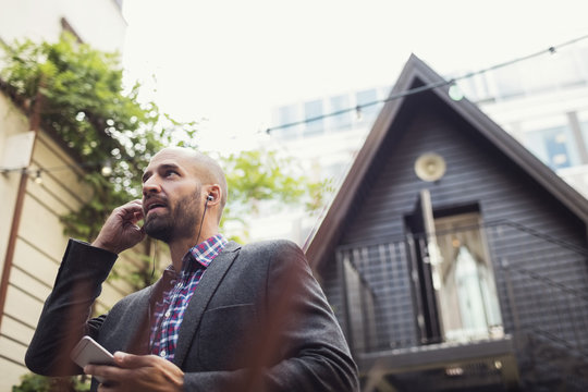 Low angle view of businessman talking through in-ear headphones at office yard