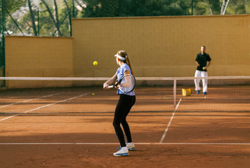 Teenage girl training tennis with her teacher