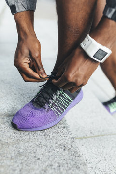 Close-up of athlete wearing smartwatch tying shoes