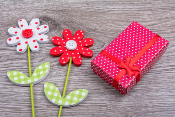 Wooden flowers with gift on wooden background