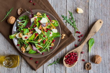 Salad with rucola and pomegranate on brown plate