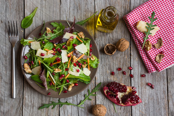 Salad with rucola and pomegranate on brown plate