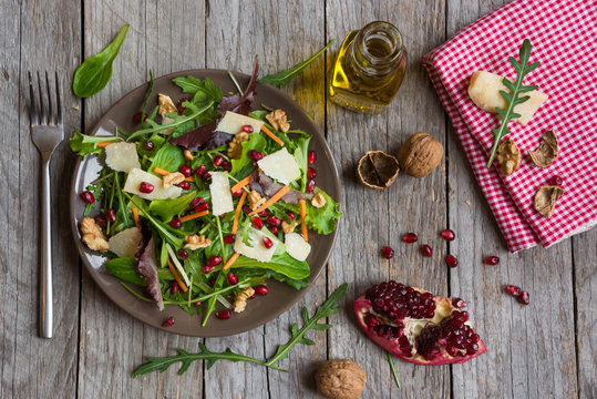 Salad with rucola and pomegranate on brown plate
