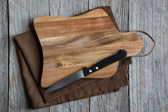 wooden cutting board with a knife and a napkin