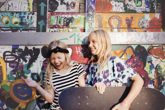 Happy friends with skateboards enjoying against multi colored wall
