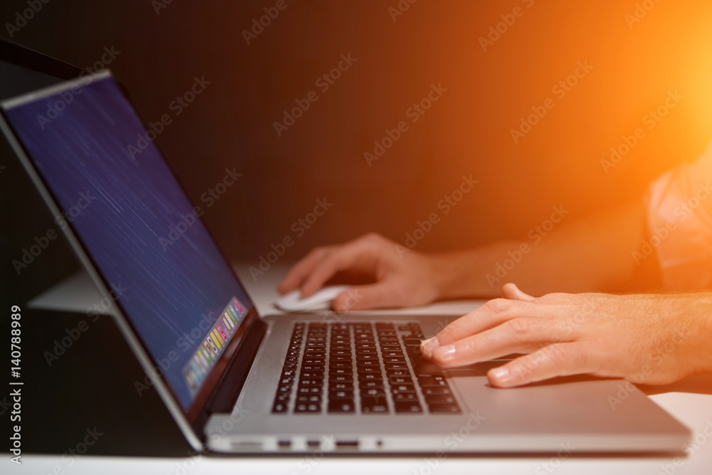 Wall mural hand typing on a keyboard of laptop with operating system screen on background