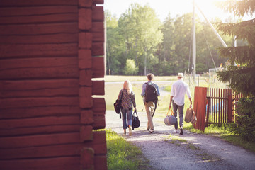 Rear view of friends with luggage walking on footpath