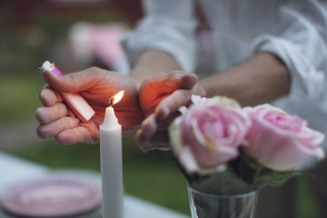Midsection of man covering lit candle on table at garden party