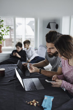 Mother And Father Shopping Online With Sons In Living Room At Home