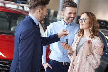 Happy couple getting keys from salesman.