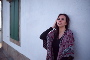 Fototapeta premium Mujer joven con un poncho apoyada en la pared de un faro