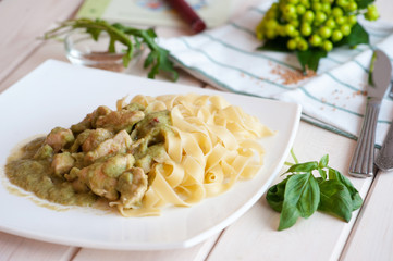 Fettuccine and chicken with fresh basil and pesto in a white plate