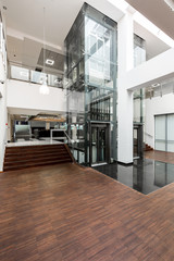 Glass lift and wooden stairs in lobby
