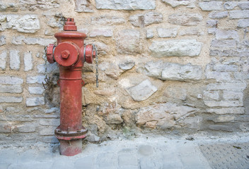 Fototapeta na wymiar Close Up to a red fire hydrant with stone wall background.