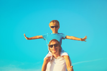 Father and little son playing on blue summer sky